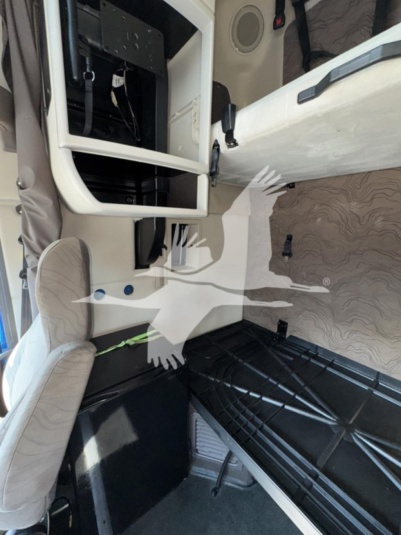 Cab interior of a Volvo VNL truck showing the sleeper area with a ladder/rack and dashboard framework, open side panel, and seat visible.