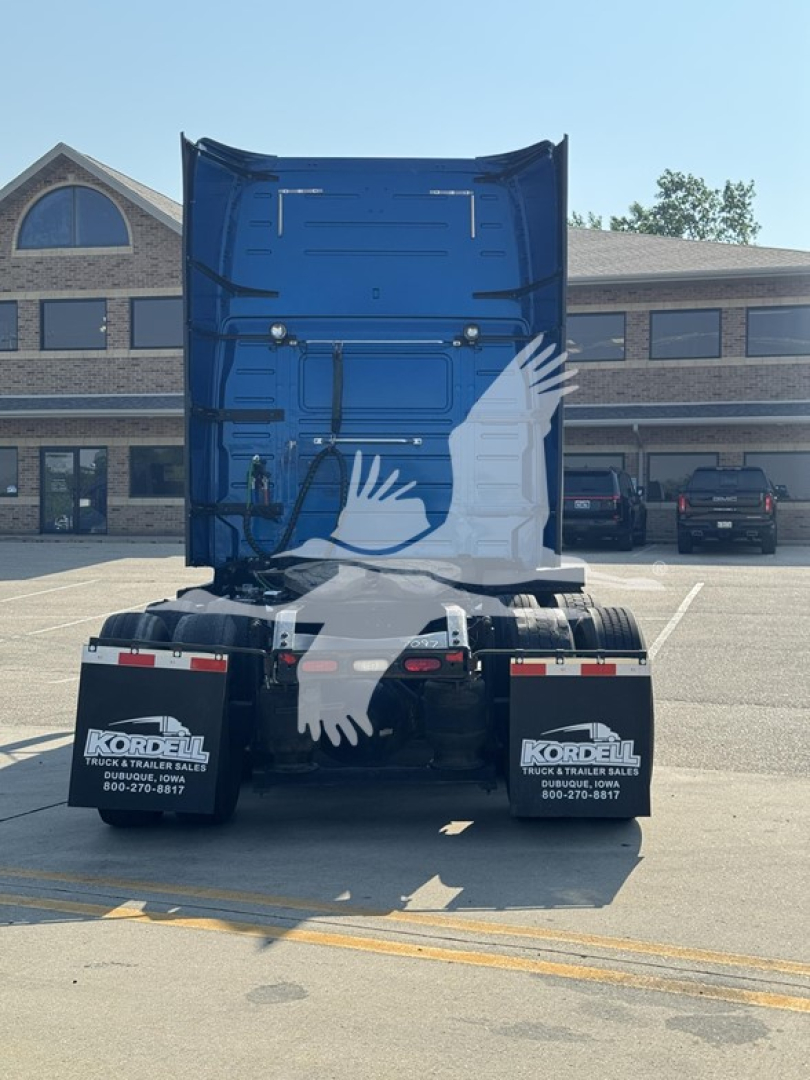 Rear view of a blue Volvo VNL truck tractor with fifth wheel, dual rear axles, mudflaps reading 'Kordell Truck & Trailer Sales' in a dealership lot.