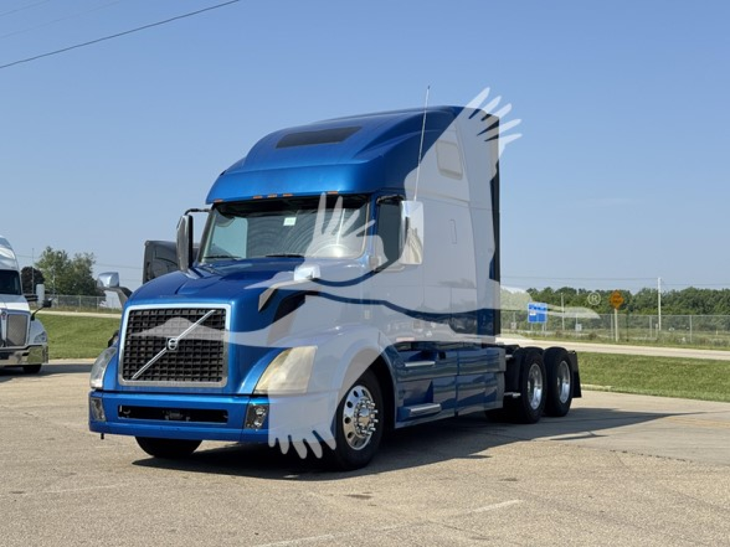 Volvo VNL truck cab in blue with sleeper, front grille and wheels visible.