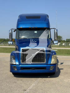 Volvo truck front view showing large grille, headlights, and blue cab in serviceable condition.