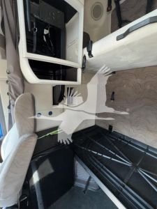 Cab interior of a Volvo VNL truck showing the sleeper area with a ladder/rack and dashboard framework, open side panel, and seat visible.