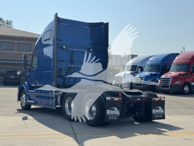 Volvo VNL64T670 sleeper tractor from rear-left side showing blue exterior, fifth wheel, and dual rear axles.