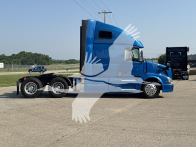 Volvo VNL64T670 sleeper cab tractor in blue, side profile view, with trailer hitch and dual rear axles visible.