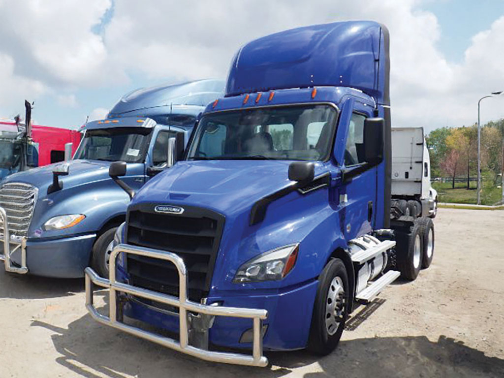 Truck cab in blue with a raised sleeper; Freightliner Cascadia-style with protective grille on front. The image shows a blue Freightliner semi-truck tractor with a safety bull bar.