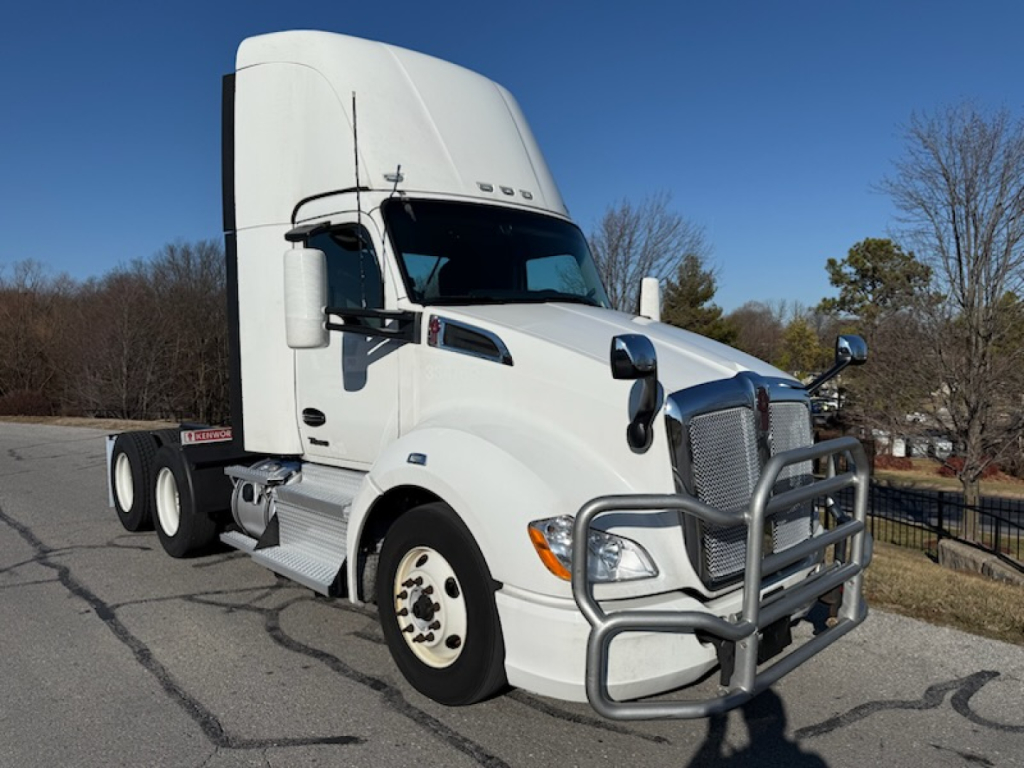 Kenworth T680 conventional daycab tractor in white, side view showing grille guard, fuel tanks, and stepped cab with large mirrors.