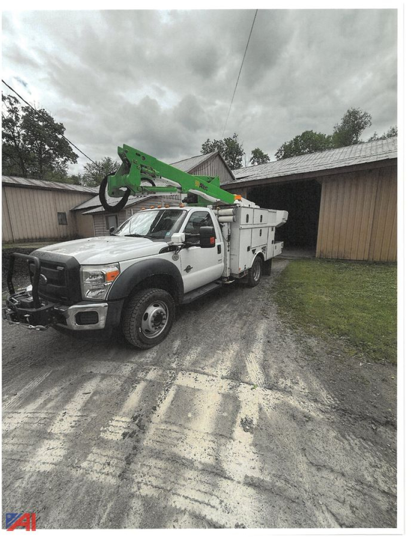 Ford F-550 bucket truck with green hydraulic boom in field, utility chassis, white service body, front bumper with grille guard.