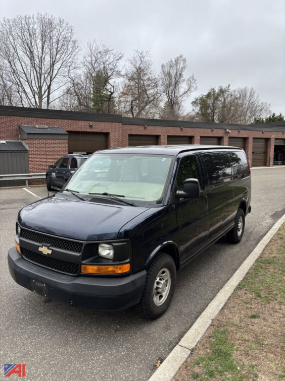 Front-left view of a black 2011 Chevrolet Express van in a parking lot showing the front grille, headlights, and side windows.