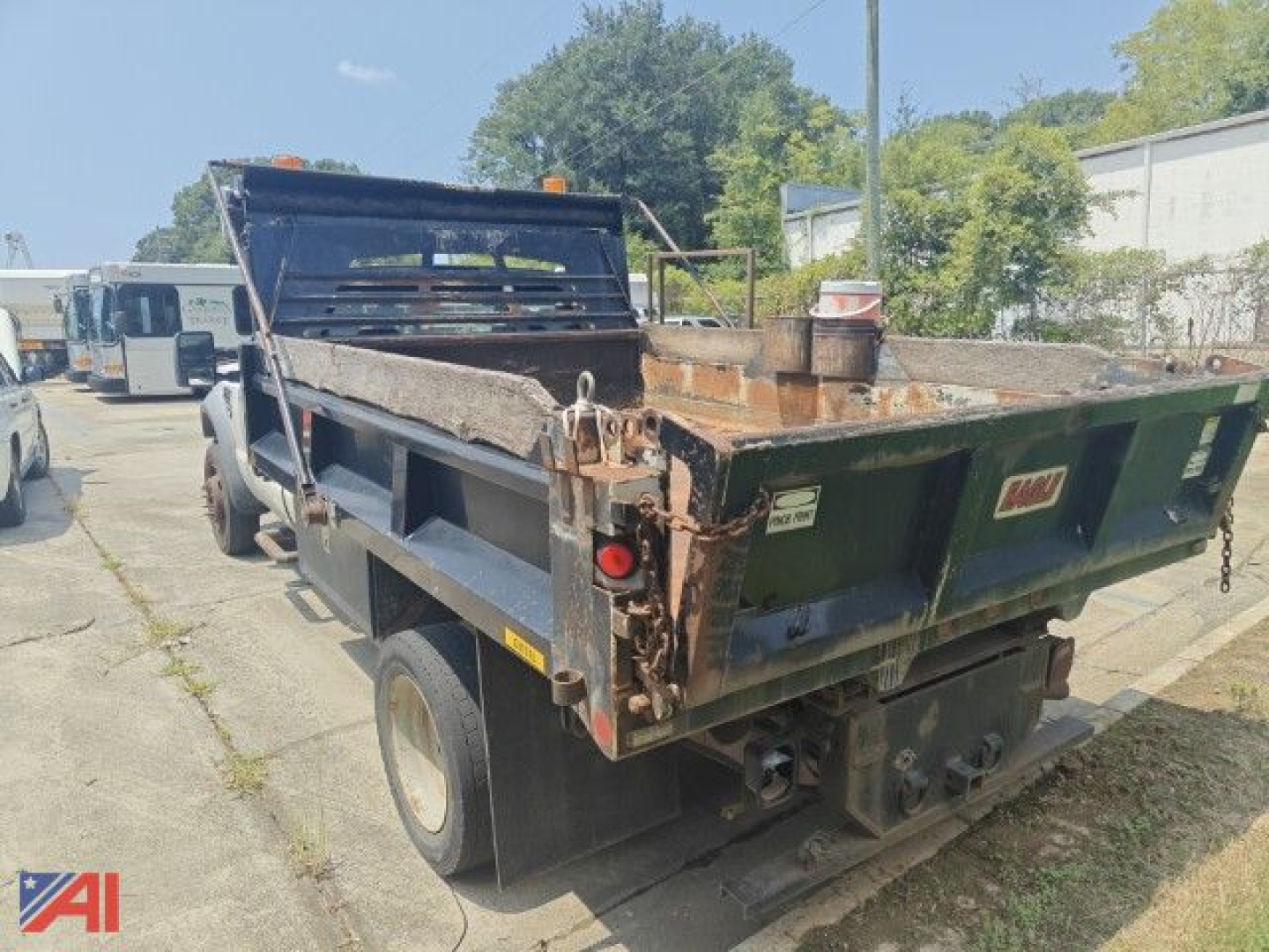 Dump truck bed visible from rear left side showing cargo area and tailgate with hooks and hydraulic components.