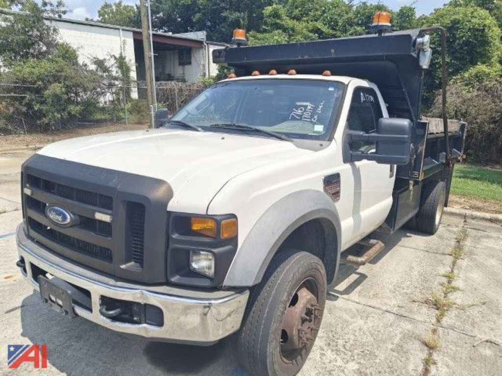 Ford F-550 Super Duty dump truck in service with dump bed raised, front grille, headlights, and orange beacon lights on cab roof.