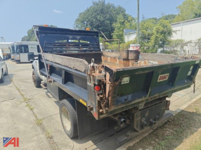 Dump truck bed visible from rear left side showing cargo area and tailgate with hooks and hydraulic components.