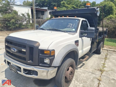 Ford F-550 Super Duty dump truck in service with dump bed raised, front grille, headlights, and orange beacon lights on cab roof.