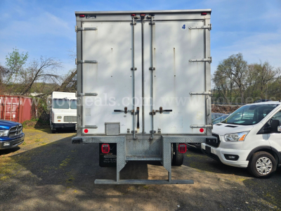 Freightliner M2 106 rear view showing cargo box doors and bumper with step, white exterior, and tail lights.