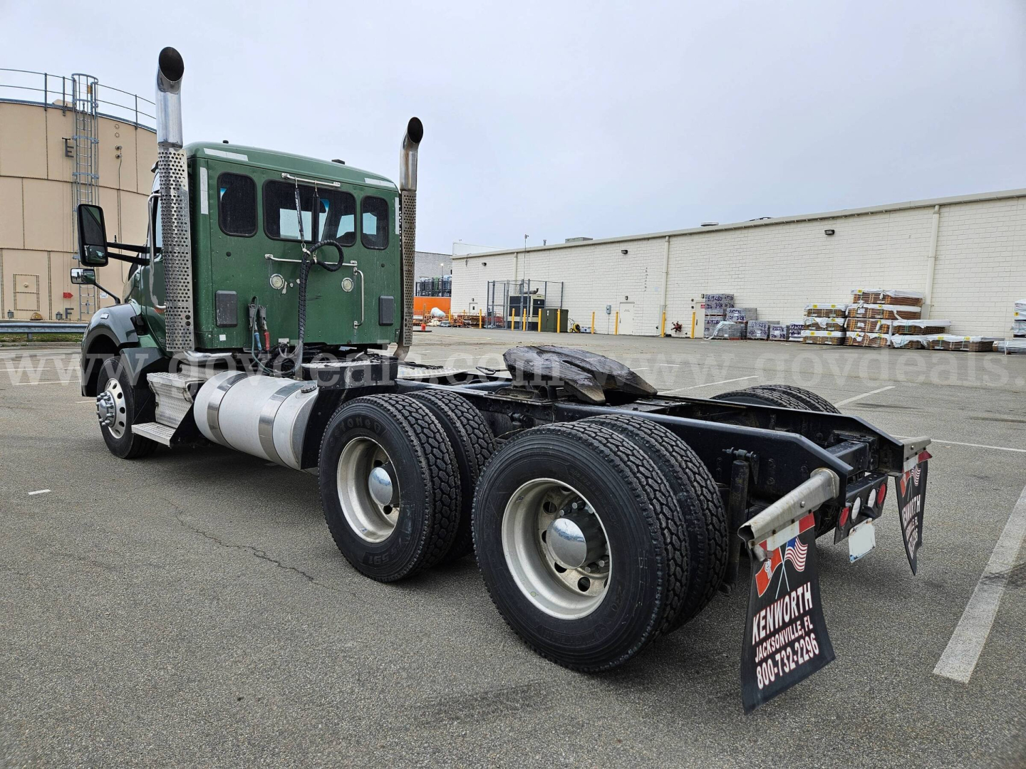 Kenworth T880 chassis and green cab with dual rear axles and fifth wheel seen from rear left side.