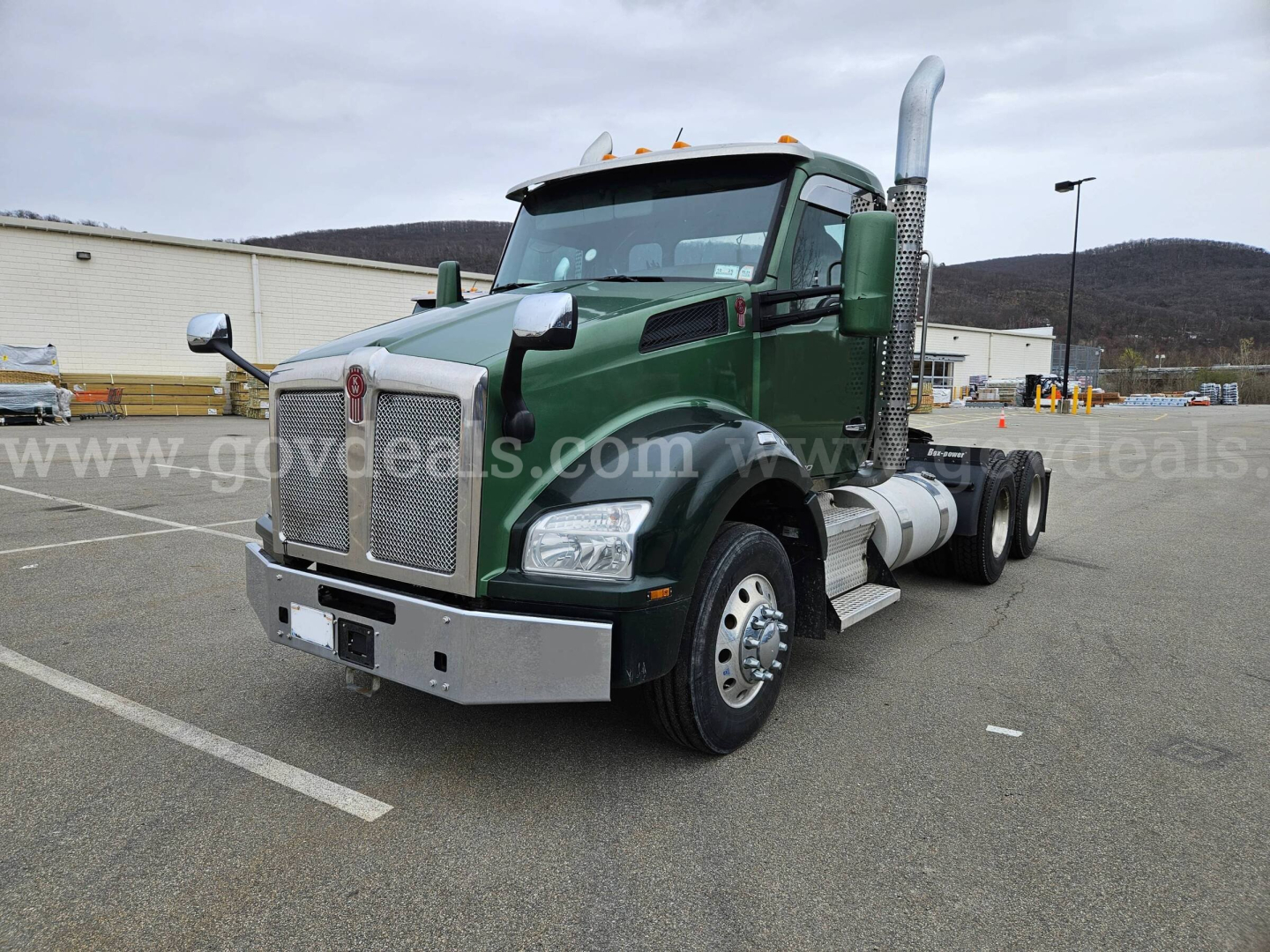 Kenworth T880 cab with green paint and chrome exhaust stacks, front bumper, and dual rear wheels. Visible text on grille and badges unclear.