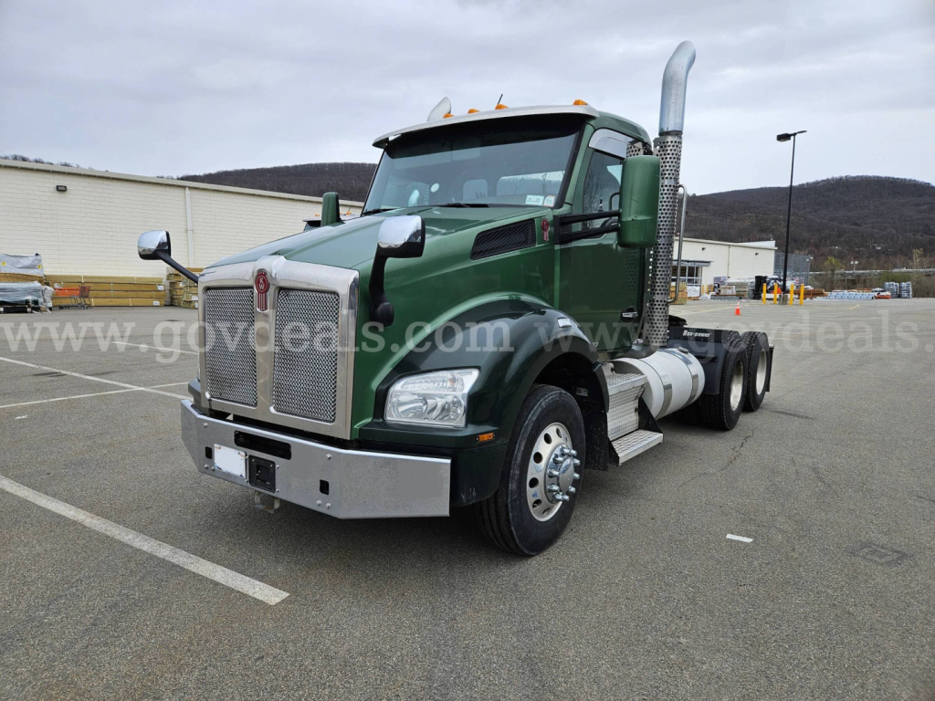 Kenworth T880 cab with green paint and chrome exhaust stacks, front bumper, and dual rear wheels. Visible text on grille and badges unclear.