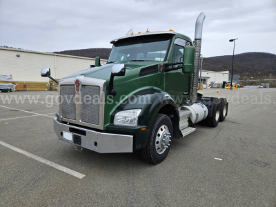 Kenworth T880 cab with green paint and chrome exhaust stacks, front bumper, and dual rear wheels. Visible text on grille and badges unclear.