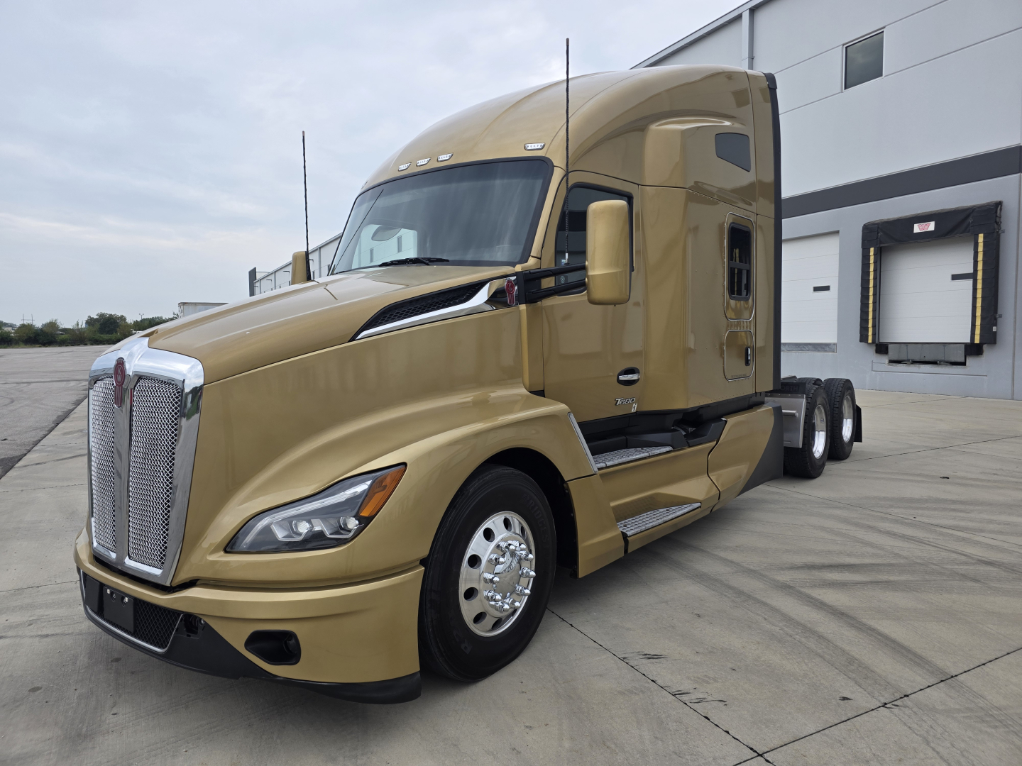 Kenworth T680 diesel truck in gold with sleeper cab, side view showing front grille, hood, and wheels.