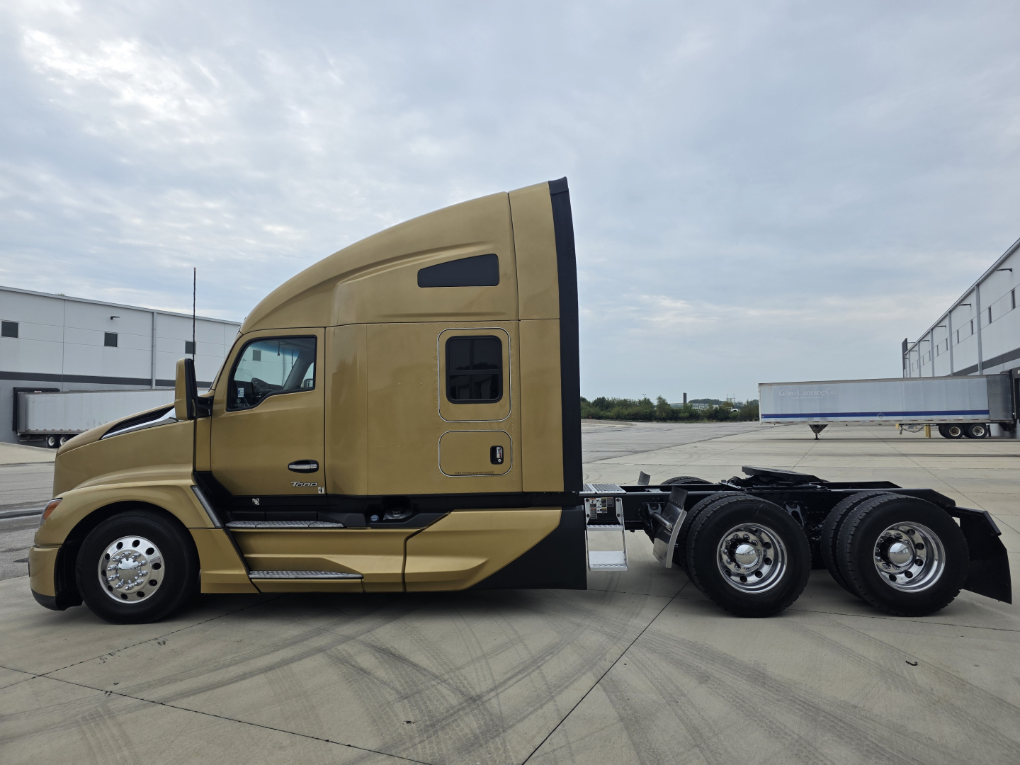 Kenworth T680 tractor side view with sleeper cab in tan color, showing chassis and rear wheels.