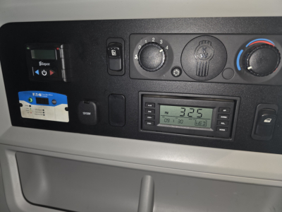 Kenworth T680 dashboard controls showing climate knobs, digital radio display, and auxiliary switches.
