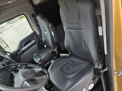 Kenworth T680 interior showing driver seat and passenger seat with dashboard area and steering wheel, black leather seats, light gray accents.