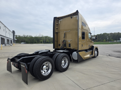 Kenworth T680 tractor with sleeper configuration, rear view showing driveline, dual rear axles, and gold paint; no visible model decals readable.