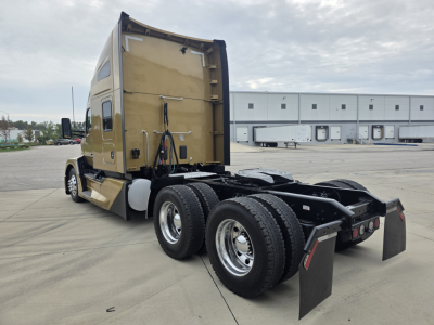 Kenworth T680 sleeper cab tractor rear view showing dual rear axles, fifth wheel, and mudflaps with beige paint.