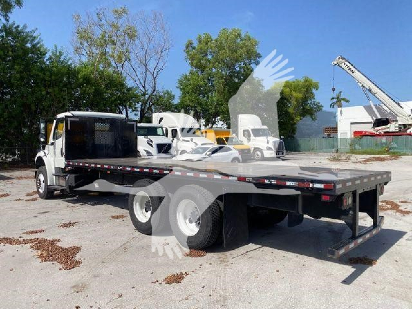 Flatbed truck on a 2018 Freightliner M2 106 chassis showing a long steel flatbed and dual rear axles.