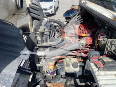 Freightliner M2 106 engine bay showing coolant reservoir, hydraulic lines, and exposed engine components in foreground.