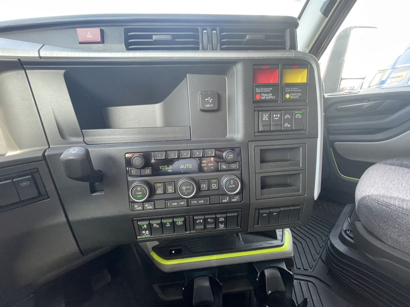 Volvo VNL64T860 truck cab interior dashboard showing climate controls, switches, and storage compartment.