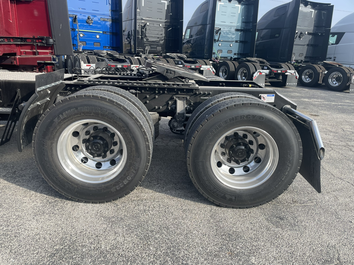 Volvo VNL64T860 chassis side view showing dual rear axles with tires and suspension, fuel lines, and frame rails.