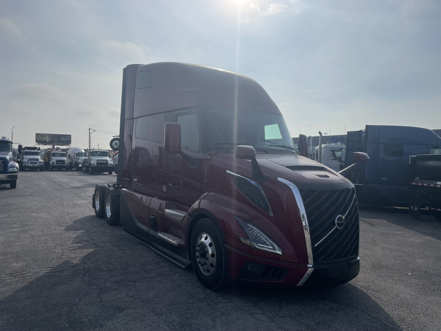 Volvo VNL64T860 tractor-trailer cab, maroon color, front grille with Volvo logo, side mirrors, daytime setting in a truck lot.