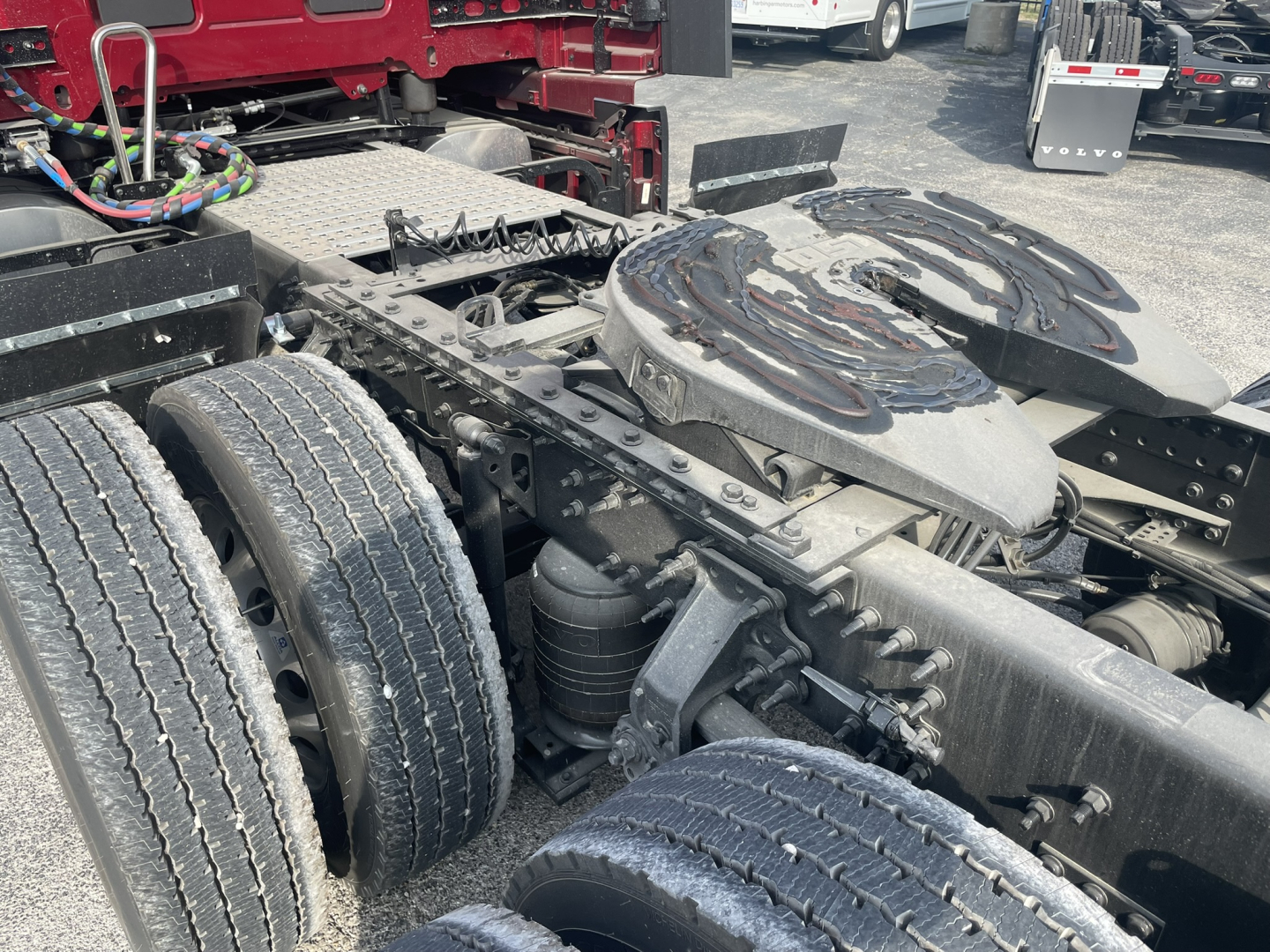 Volvo VNL64T860 tractor chassis showing fifth-wheel, dual rear wheels, and drivetrain components with fuel lines and wiring; some grime on surfaces.