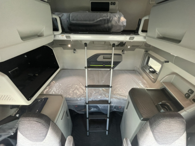 Volvo VNL64T860 cab interior showing bunk bed with ladder, storage compartments, and overhead panels.