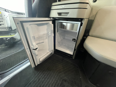 Volvo VNL64T860 truck interior showing open cab mini fridge/freezer compartment with empty shelves and door open.