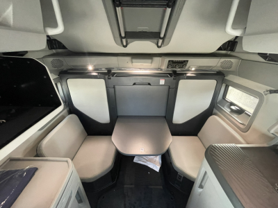 Volvo VNL64T860 sleeper cab interior showing seating area and table with overhead storage and ambient lighting.