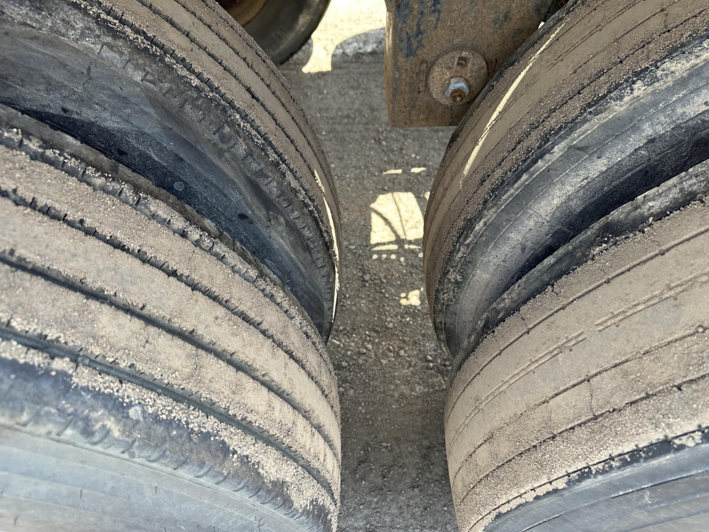 Pneumatic trailer wheels and gap between dual tires, with dust on tread and rubber.