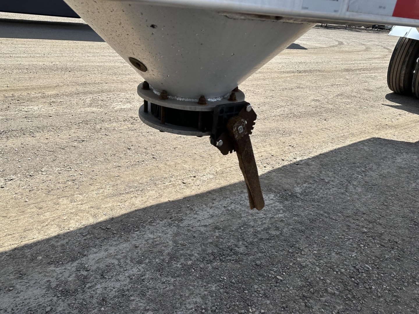 Pneumatic gravity drop trailer bottom hopper with valve lever and flange showing undercarriage, steel cone and valve stem.