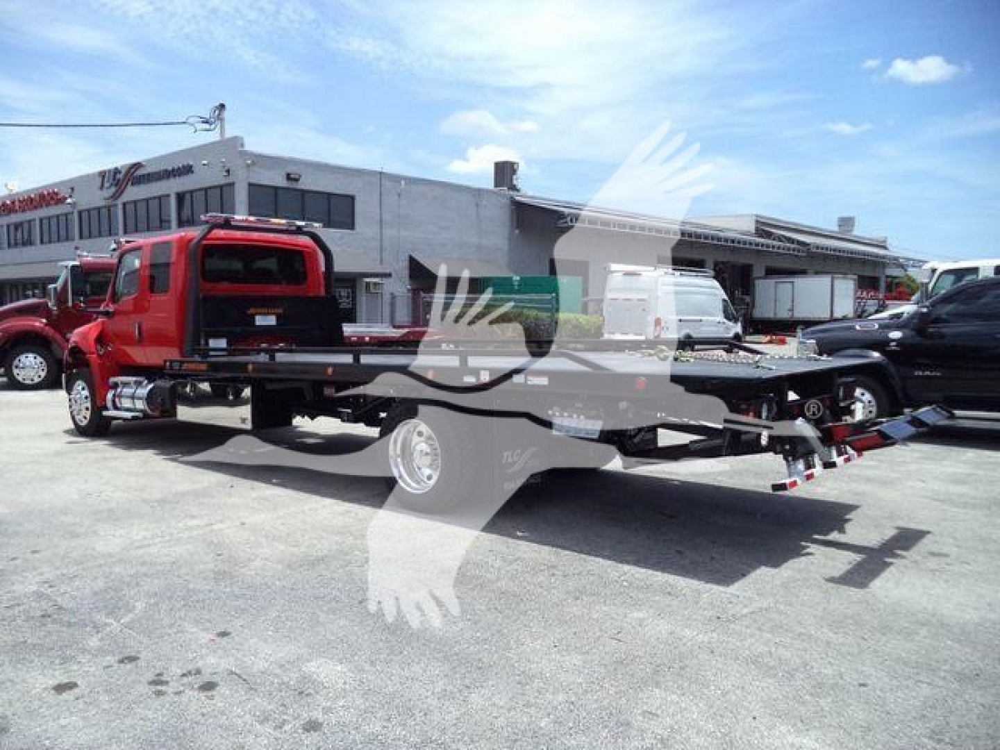 Flatbed tow truck with red cab and black platform in dealership lot; VIN 1HTEUMML1VS478884 and stock J78884 visible on listing page.