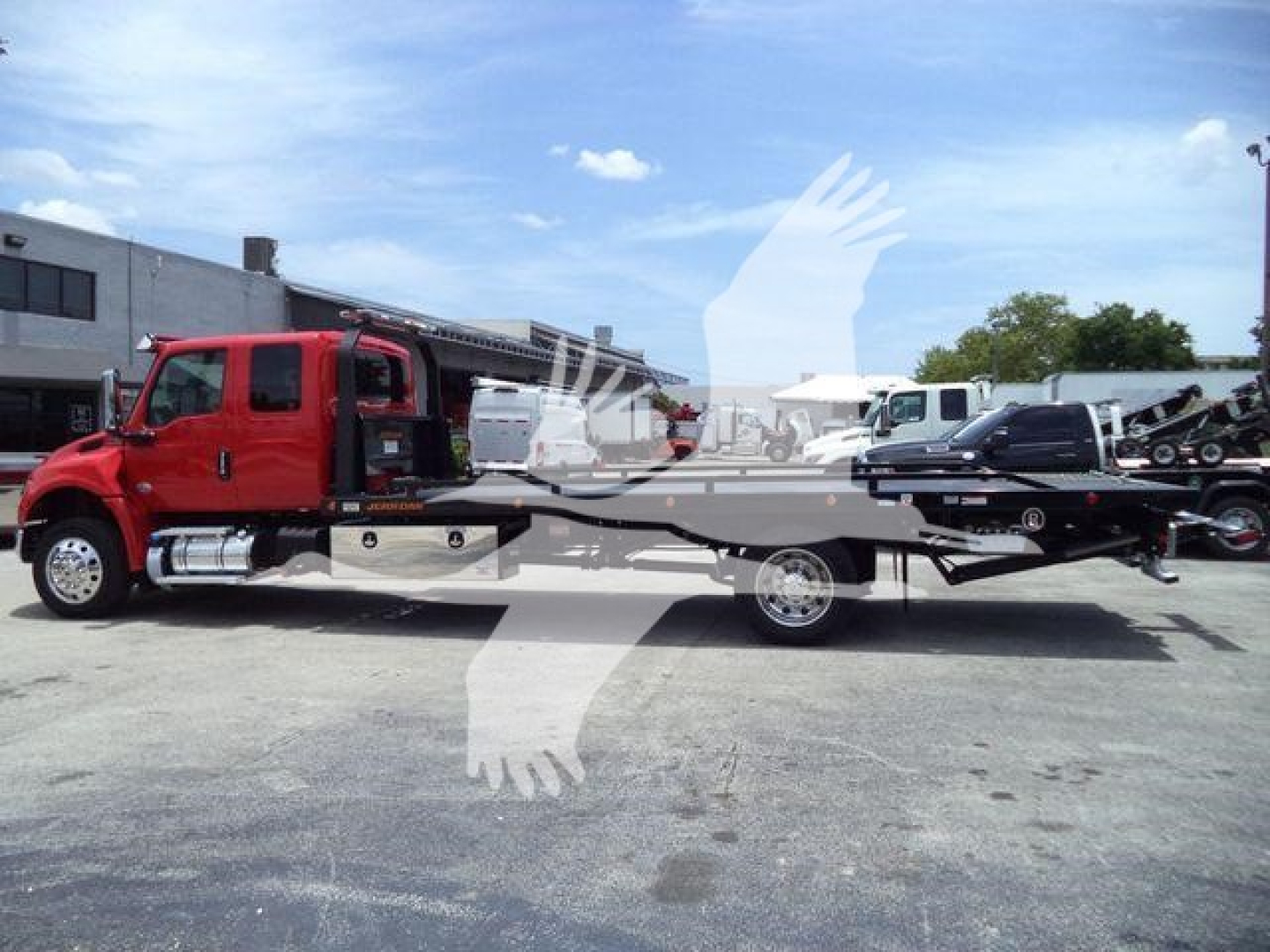 Tow truck with a red cab and a flatbed rollback body, VIN 1HTEUMML1VS478884 visible, parked outdoors at a dealership lot.
