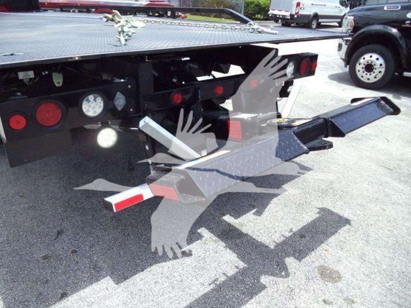 Truck rollback vehicle rear view showing hydraulic flatbed and loading ramps at the back.