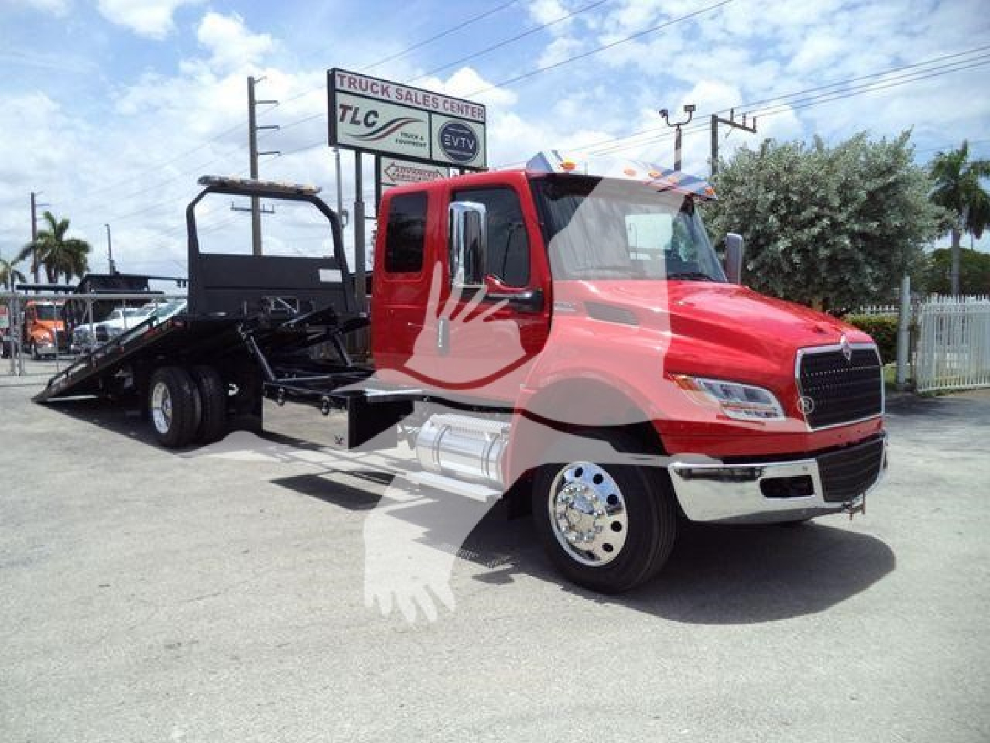 International MV rollback truck front-left view showing red cab and black rollback bed with chrome bumper and wheel rims.