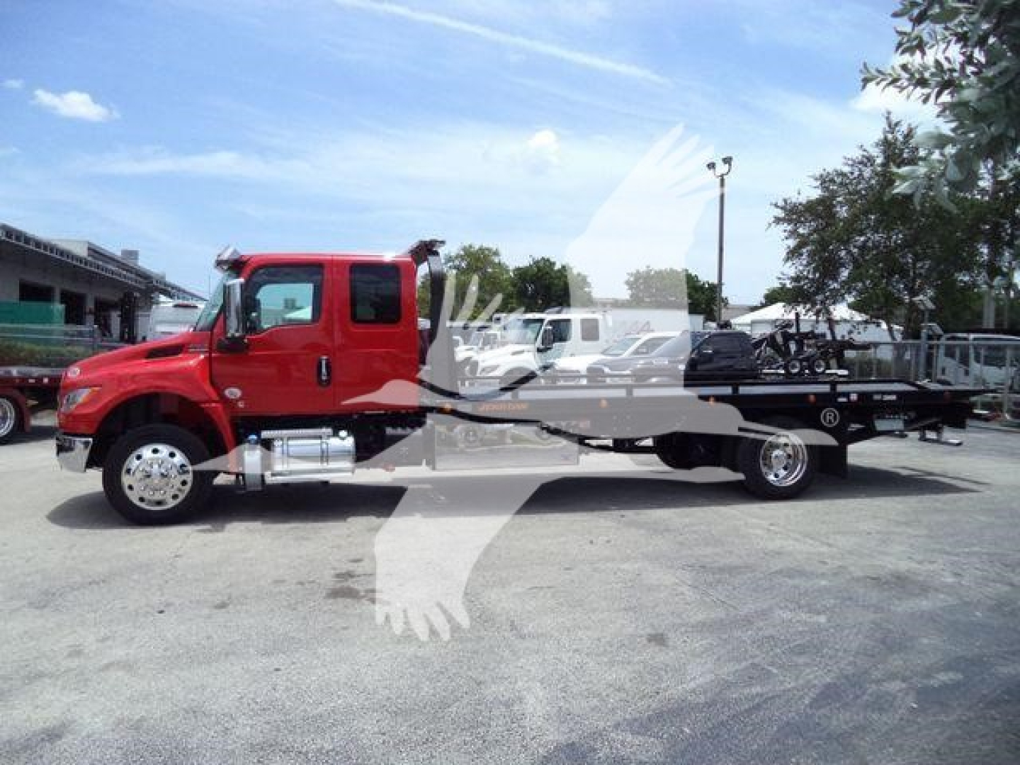 Side view of a red International MV rollback truck with a long flatbed and towing equipment.