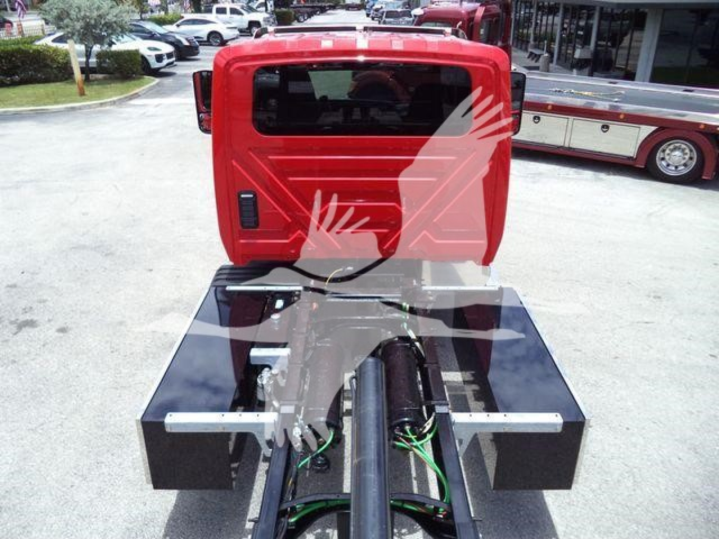 Truck cab and rollback bed showing VIN sticker and hydraulic lines with two black tool boxes on either side.