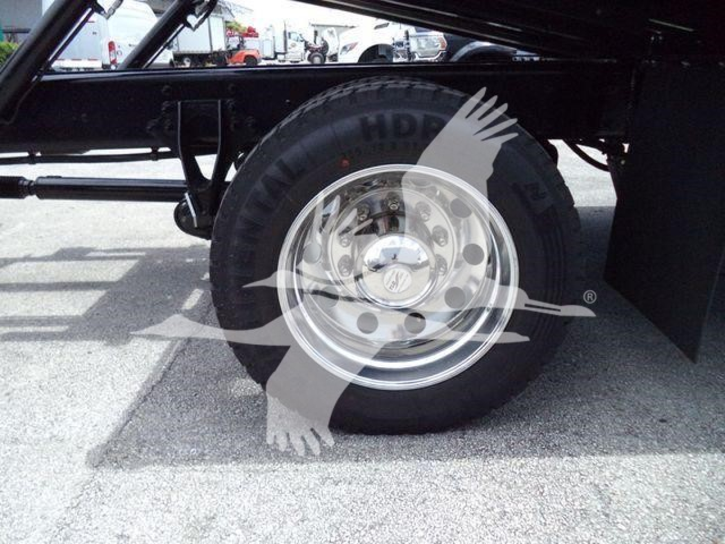 Wheel and tire of a truck chassis showing a polished steel rim and black tire with sidewall text.