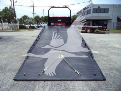 Tow truck rollback bed of a 2027 International MV showing hydraulic ramps and safety chains.