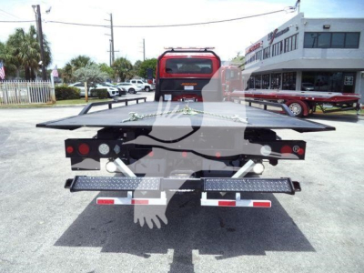 Tow truck rollback rear view showing platform bed and taillights, with reflective side rails and rear bumper lights.