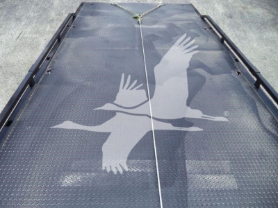 Truck bed or loading platform with a large white bird graphic, likely a crane, on a diamond plate surface; rope and anchors at top center.