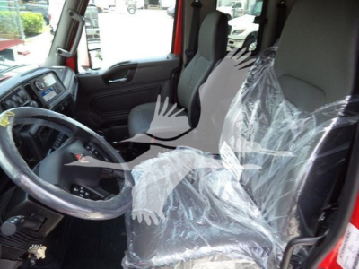 Truck interior showing steering wheel and driver's seat with plastic covering.