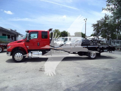 Side view of a red International MV rollback truck with a long flatbed and towing equipment.