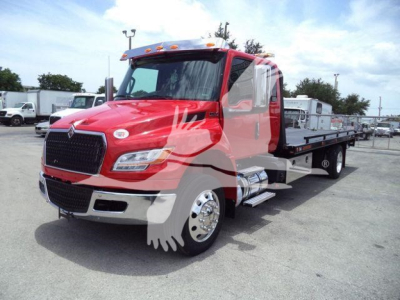 Truck on a rollback tow bed showing red cab and flatbed with chrome exhaust and side steps.